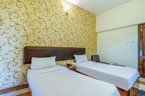 two beds in a room with yellow wallpaper at Hotel Executive in Lucknow