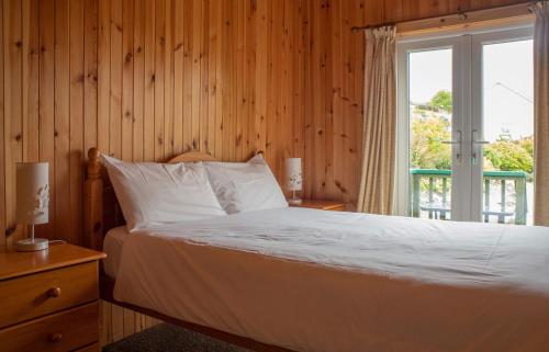 ポートリーにあるSkye Garden Accommodationの窓とベッドサイドが備わる木造の部屋のベッド1台分です。