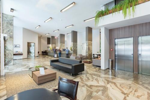 a lobby with a couch and a table and chairs at Slaviero Blumenau in Blumenau
