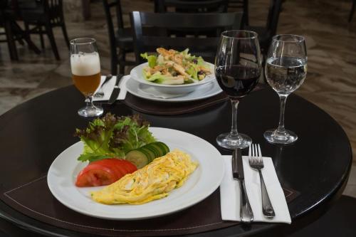 a table with two plates of food and glasses of wine at Slaviero Blumenau in Blumenau