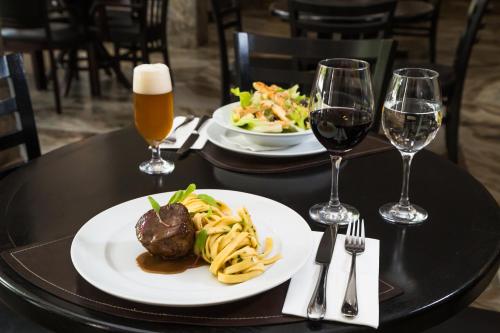 a table with two plates of food and two glasses of wine at Slaviero Blumenau in Blumenau