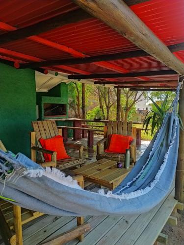 a hammock on a deck with chairs under a roof at Rancho la Casual in Punta Del Diablo