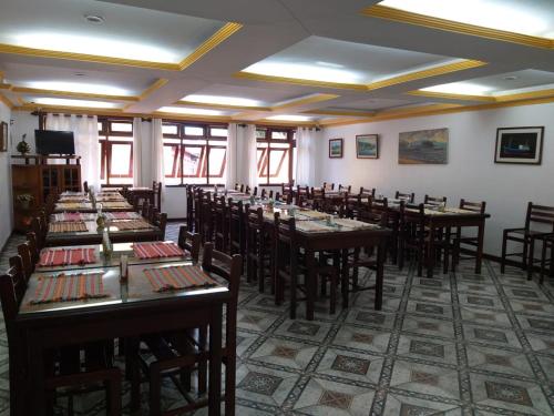 a dining room with tables and chairs and windows at Pousada Juliana in Abraão