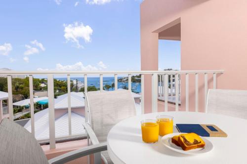 a table with two glasses of orange juice on a balcony at Elysian Beach Resort in St Thomas