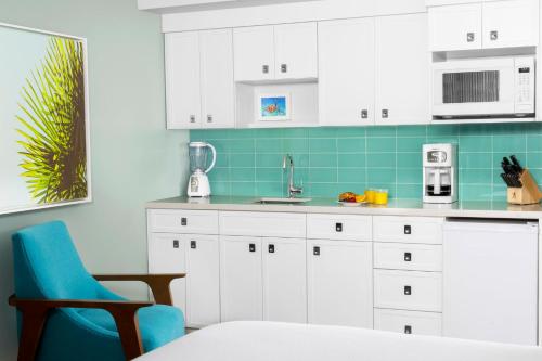 a kitchen with white cabinets and a blue chair at Elysian Beach Resort in St Thomas