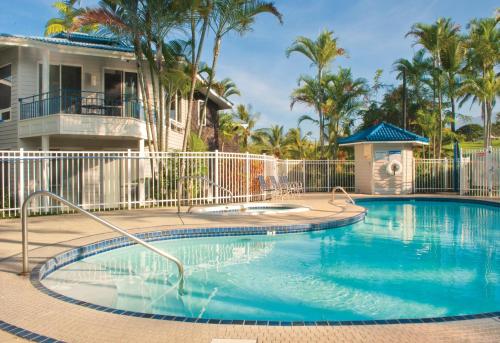 a swimming pool in front of a house with palm trees at Wyndham Mauna Loa Village in Kailua-Kona