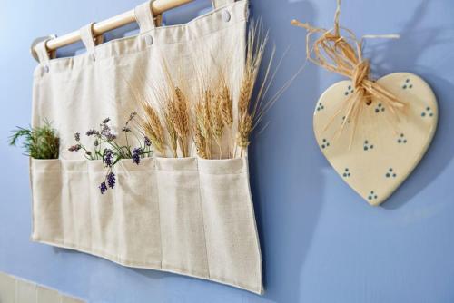 a cloth bag with dried flowers and a heart on a blue wall at Appartamentino IL NIDO vista mare in Recanati