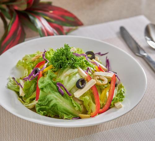 a white plate with a salad on a table at Regenta Inn Grand-ORR, Mahadevapura in Bengaluru