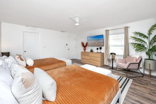 a bedroom with two beds and a pink chair at Clearwater Cabana - Gorgeous Home with Heated Pool in Clearwater