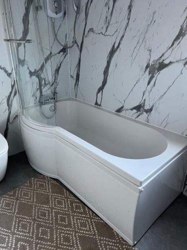 a white bath tub sitting in a bathroom at 4 bed bungalow near Airport in Edinburgh