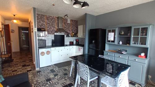 une cuisine avec des armoires blanches et un réfrigérateur noir dans l'établissement RESIDENCE DE LA MER - Appartement 2 chambres très spacieux A 2 pas du Port et de la Plage - Clim - parking, à Saint-Cyprien