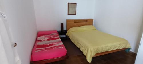 a small bedroom with a bed and a red suitcase at La casita de Miramar in Miramar