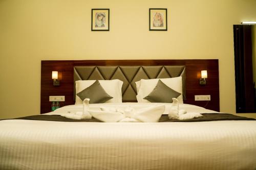 a bedroom with a large bed with white sheets and pillows at Hotel Ballerina in Tinsukia