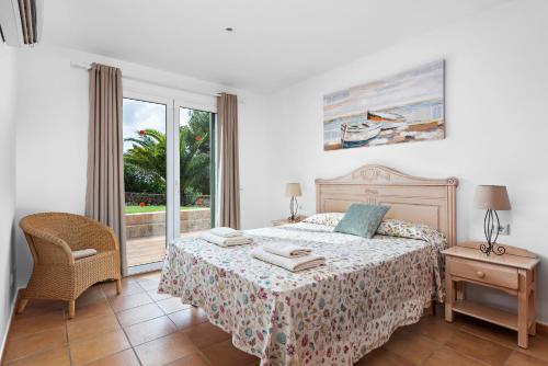 a bedroom with a bed and a chair and a window at Villa Iris Torret by Escape Home in Sant Lluis