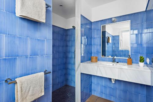 a blue tiled bathroom with a sink and a mirror at Villa Iris Torret by Escape Home in Sant Lluis