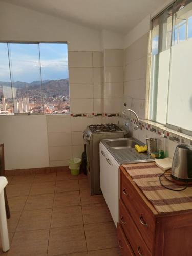 cocina con fregadero, fogones y ventana en Arcopata Apartamentos, en Cusco