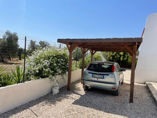 a small car parked under a wooden pergola at Villa Connie in Serranova