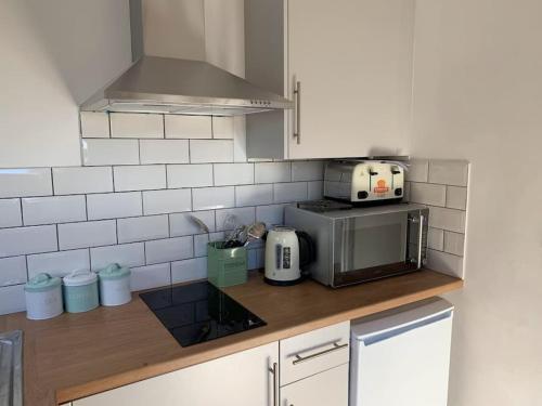 a kitchen with a counter with a toaster and a microwave at The Captain's Retreat, Quiet 1 Bed Dog Friendly in Puncknowle