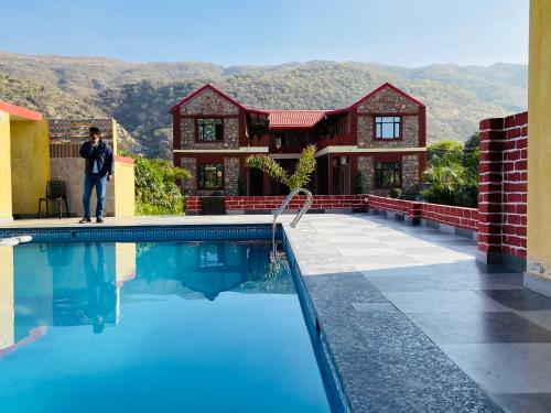 a man standing in front of a house with a swimming pool at Pushkar Retreat Resort - The Nature and Mountain View Resort ,Pushkar in Pushkar