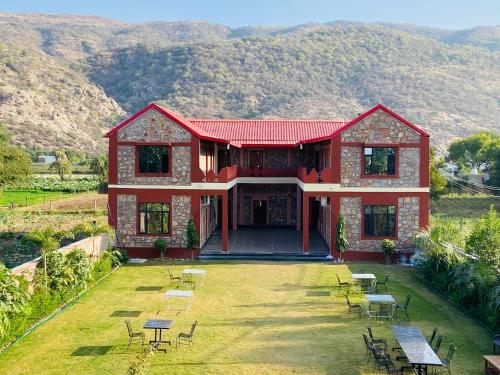 a red house with tables and chairs in a yard at Pushkar Retreat Resort - The Nature and Mountain View Resort ,Pushkar in Pushkar