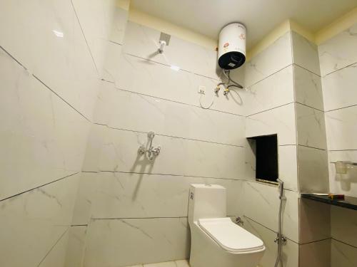 a white bathroom with a toilet and a blow dryer on the wall at Pushkar Retreat Resort - The Nature and Mountain View Resort ,Pushkar in Pushkar