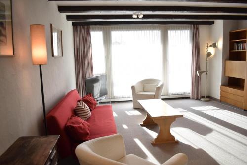 a living room with a red couch and a table at Astoria (104 Mu) in Lenzerheide