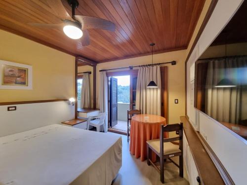 a bedroom with a bed and a table and chairs at APARTAMENTO GRAMADO HOTEL in Gramado