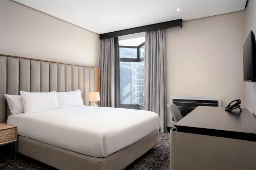 a hotel room with a white bed and a desk at Premier Splendid Inn Umhlanga in Durban