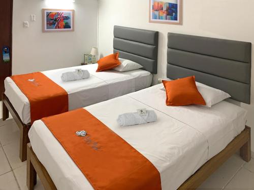 two beds in a room with orange and white at Hostal Resident in Piura