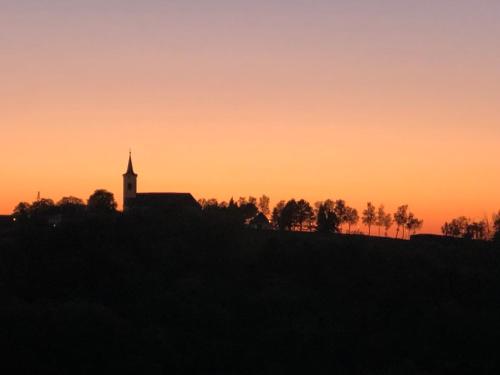 a church on top of a hill at sunset at Der Hof am Wald in Weichselbaum
