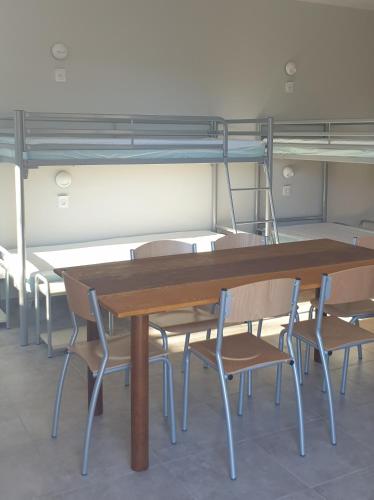 stół i krzesła w pokoju z łóżkiem piętrowym w obiekcie Rambaud Refuge Pèlerins w mieście Rambaud