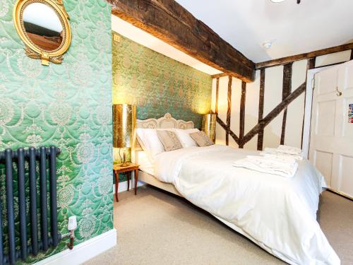 een slaapkamer met een bed en een groene muur bij Plas Dolguog in Machynlleth