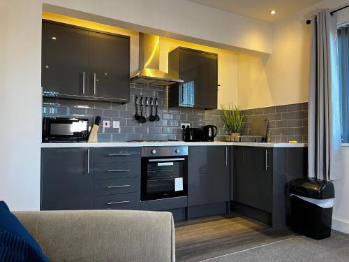 a kitchen with black cabinets and a counter top at Lovely Serviced Apartment - Near Doncaster Hospital in Doncaster