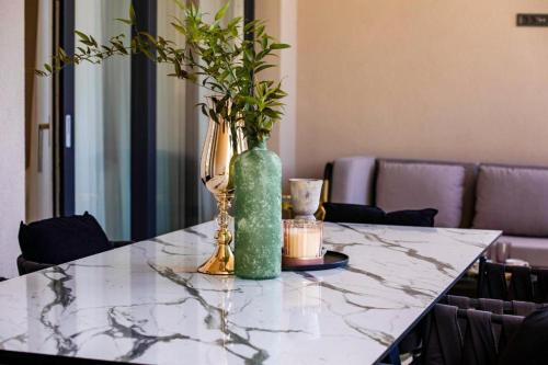 a marble table with two vases and a candle on it at Villa Nina - Apartments with pool near the sea in Rabac