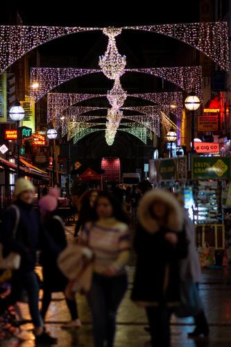 a crowd of people walking down a street with christmas lights at Latroupe Jacobs Inn in Dublin
