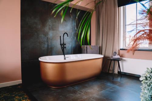 een badkamer met een bad en een raam bij Boutique Lodge Zandvoort in Zandvoort