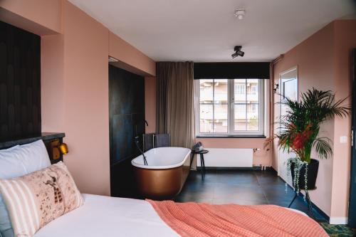 - une chambre avec un lit, une baignoire et une fenêtre dans l'établissement Boutique Lodge Zandvoort, à Zandvoort