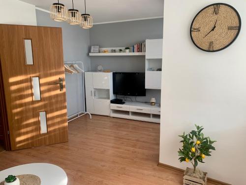 salon z telewizorem i zegarem na ścianie w obiekcie Apartament Joanna 2 parter w mieście Gliwice