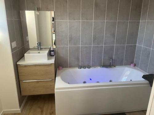 een badkamer met een wit bad en een wastafel bij WAGNER’studio BALNÉO’terrasse au calme in Chasse-sur-Rhône