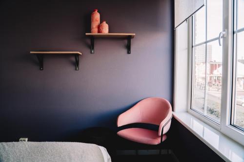 une chaise rose assise dans une pièce avec fenêtre dans l'établissement Boutique Lodge Zandvoort, à Zandvoort