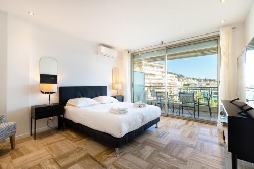 sypialnia z łóżkiem i dużym oknem w obiekcie Agence des Résidences - Appartements privés du 45 CROISETTE - Superieur w Cannes