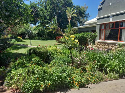 a garden in front of a house at La Pension Guest House in Oudtshoorn