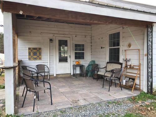 a patio with chairs and a table in front of a house at The Schoolhouse vintage home on the farm 