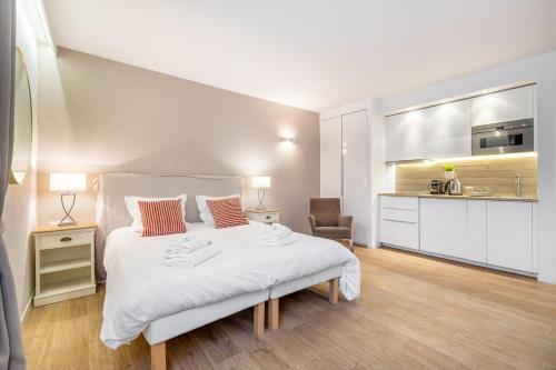 a bedroom with a large white bed and a kitchen at Agence des Résidences - Appartements privés du 45 CROISETTE - Superieur in Cannes