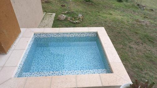 una piscina con azulejos azules en un patio en Cabaña La Joaquina - Villa Giardino en Villa Giardino