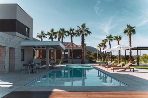 a villa with a swimming pool and palm trees at Insulae Resort in Cefalù