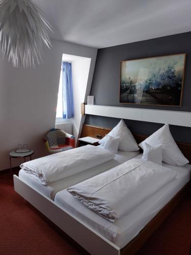 a bedroom with a large bed with white sheets and pillows at Hotel Garni "Brauerei Keller" in Miltenberg