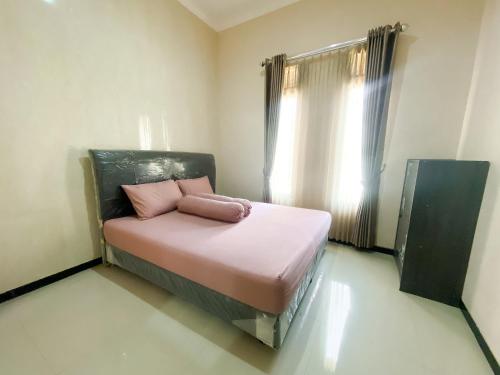 a bedroom with a bed with pink sheets and a window at Vila Diamond Batu in Songgoriti