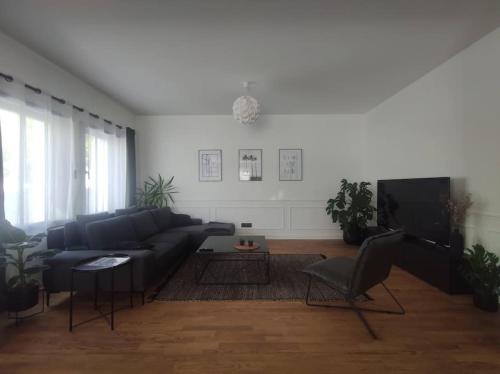 ein Wohnzimmer mit einem schwarzen Sofa und einem TV in der Unterkunft villa_lumiere_la_rochelle avec spa à 800m de l'océan in La Rochelle