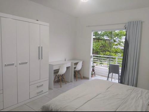 Habitación blanca con escritorio y mesa en Pousada Pontal Jurerê, en Florianópolis